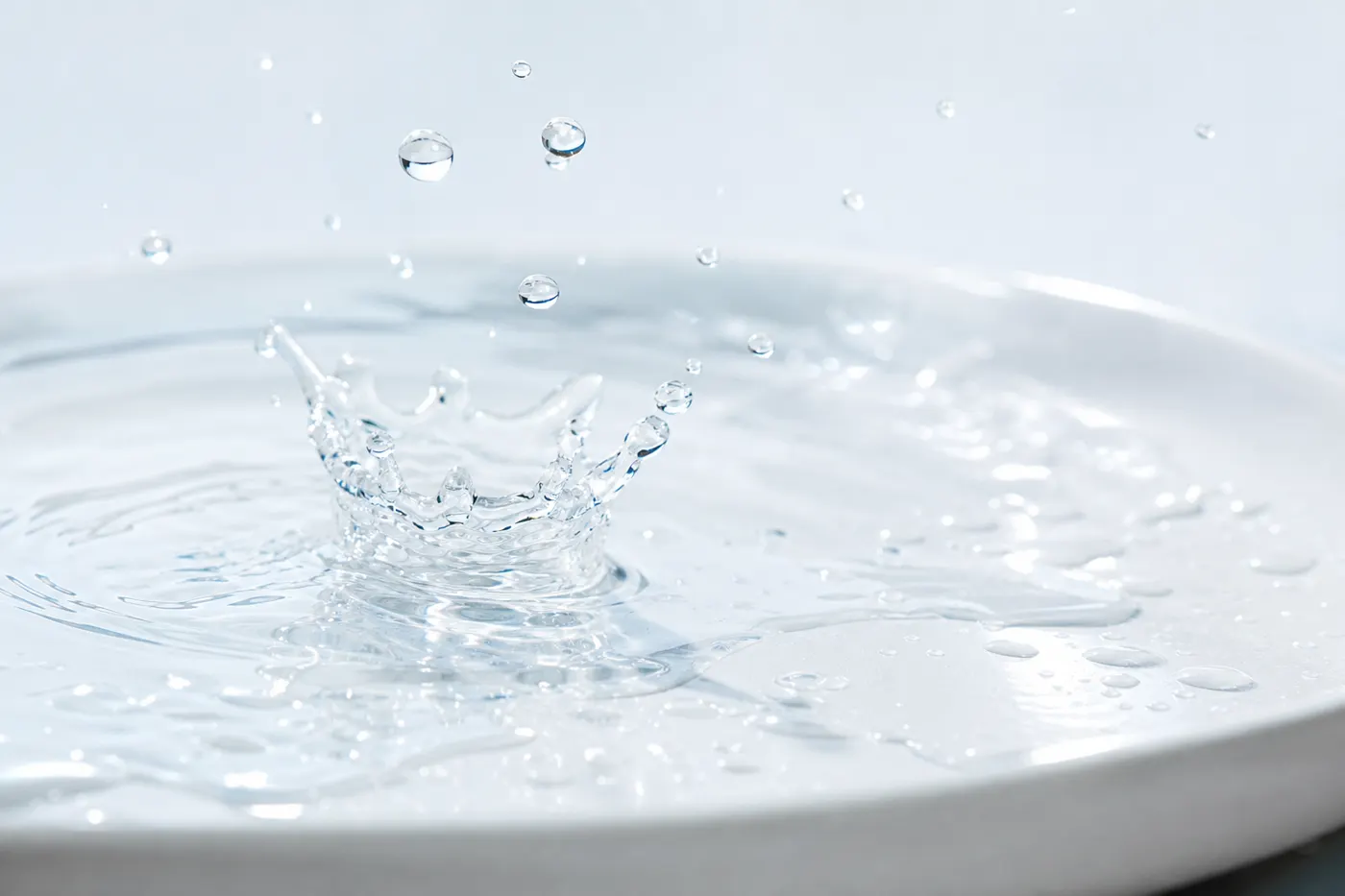 Gota de agua cristalina impactando sobre una superficie blanca